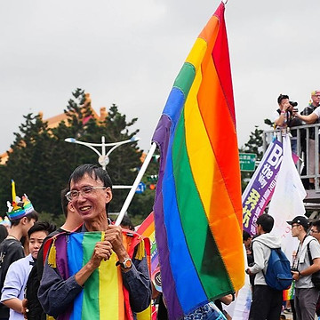A person holding a rainbow flag
Description automatically generated